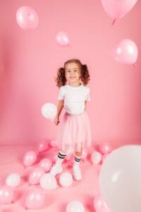Petite fille qui joue avec des ballons roses